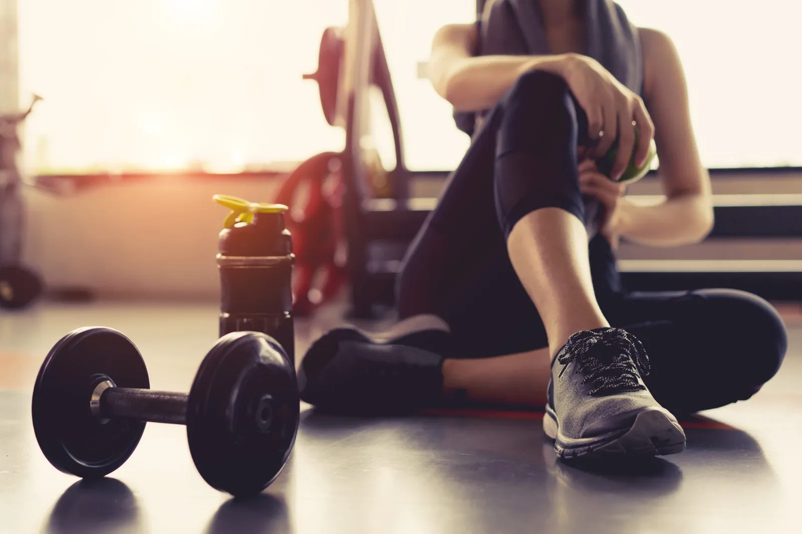 Kézisúlyzó és pihenő sportoló a konditerem padlóján